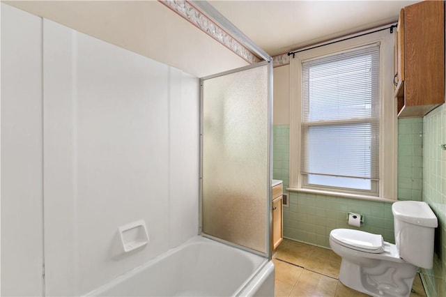 bathroom with toilet, combined bath / shower with glass door, tile walls, and tile patterned floors