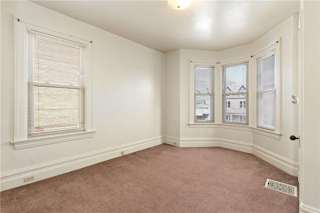 empty room featuring light carpet, visible vents, and baseboards