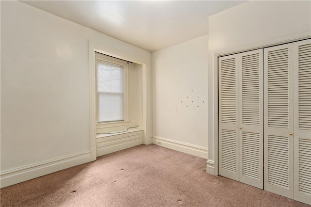 unfurnished bedroom with a closet, carpet flooring, and baseboards