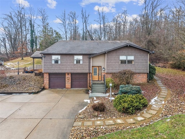 raised ranch featuring a garage, driveway, and brick siding