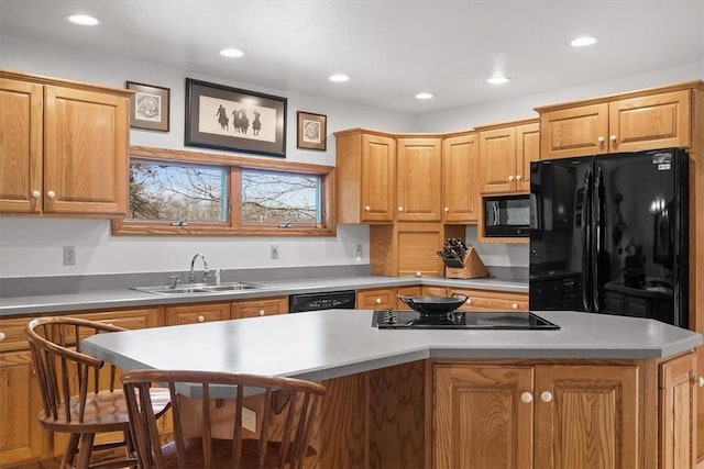 kitchen featuring recessed lighting, a kitchen island, a sink, black appliances, and a kitchen breakfast bar