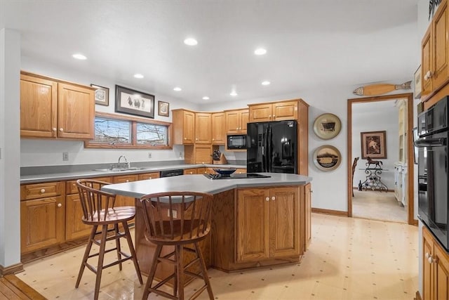 kitchen featuring a kitchen island, light floors, black appliances, a sink, and recessed lighting