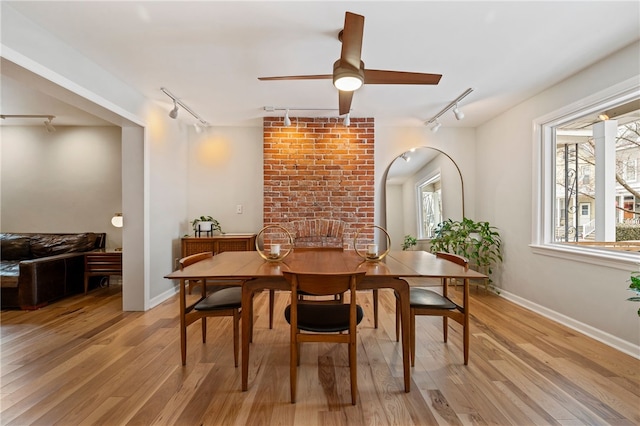 dining area with light wood finished floors, ceiling fan, baseboards, and rail lighting