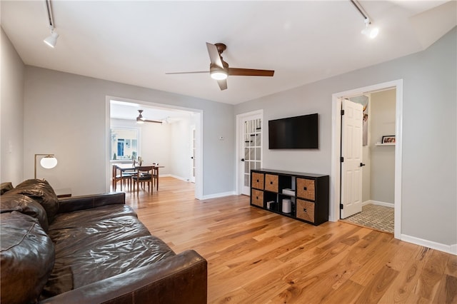 living area featuring a ceiling fan, track lighting, light wood-style flooring, and baseboards