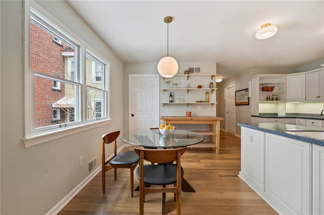 dining room featuring light wood-style floors, visible vents, and baseboards