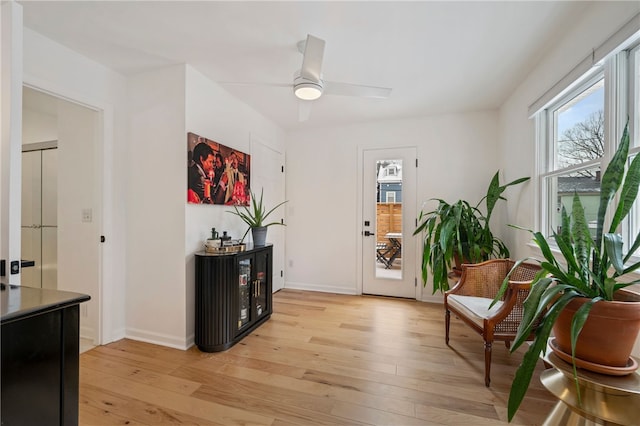 foyer entrance with baseboards, light wood-style flooring, and a ceiling fan