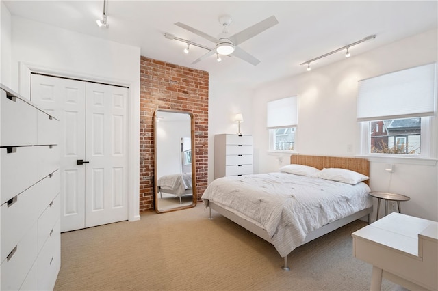 bedroom with rail lighting, a closet, light colored carpet, and ceiling fan