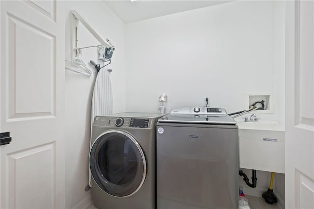 washroom with laundry area, separate washer and dryer, and a sink