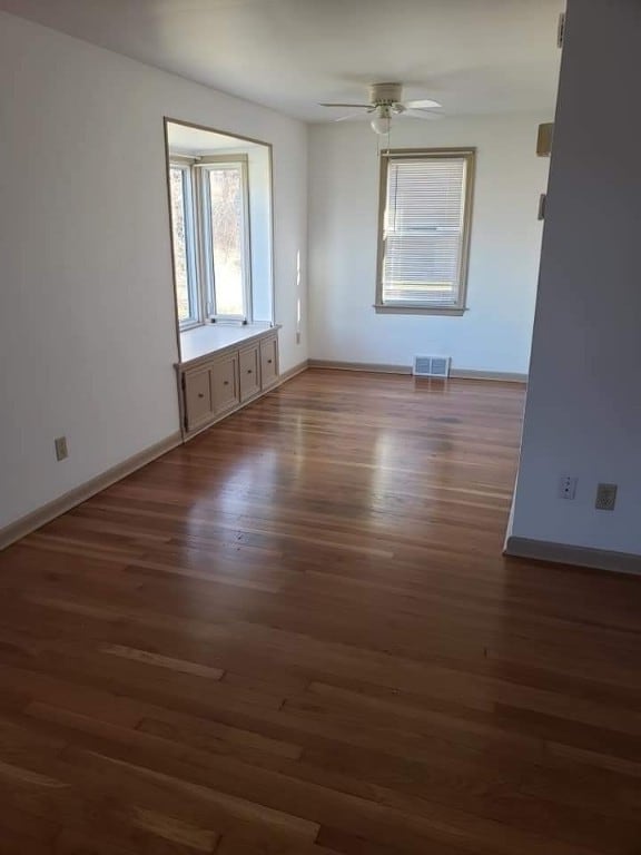 unfurnished room featuring visible vents, ceiling fan, baseboards, and wood finished floors