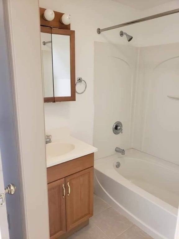 bathroom with bathtub / shower combination, vanity, and tile patterned floors