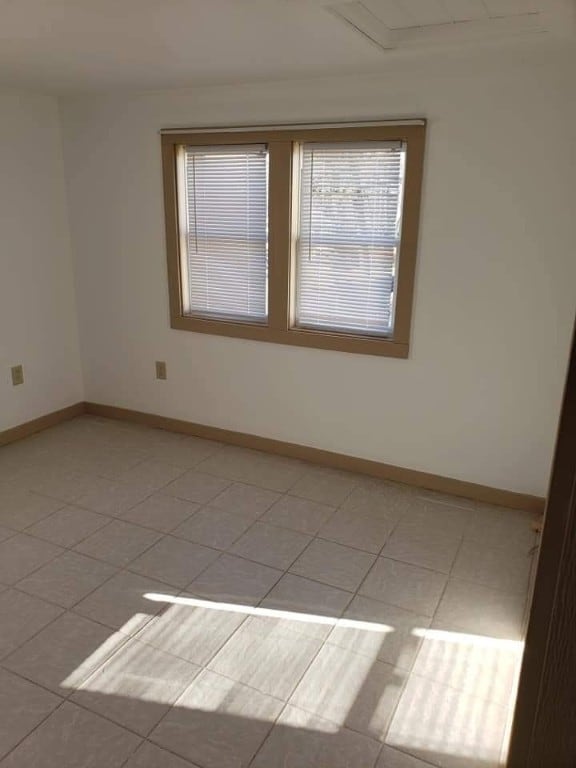 spare room featuring baseboards and light tile patterned floors