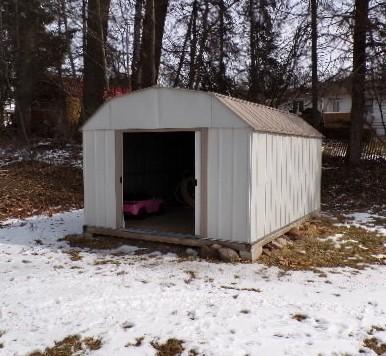 snow covered structure featuring a storage shed and an outdoor structure