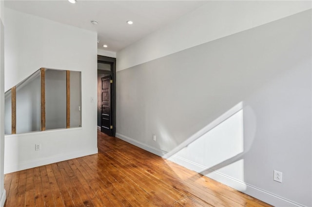 unfurnished room featuring recessed lighting, wood-type flooring, and baseboards