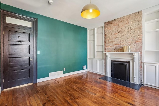 unfurnished living room featuring baseboards, built in shelves, visible vents, and a fireplace