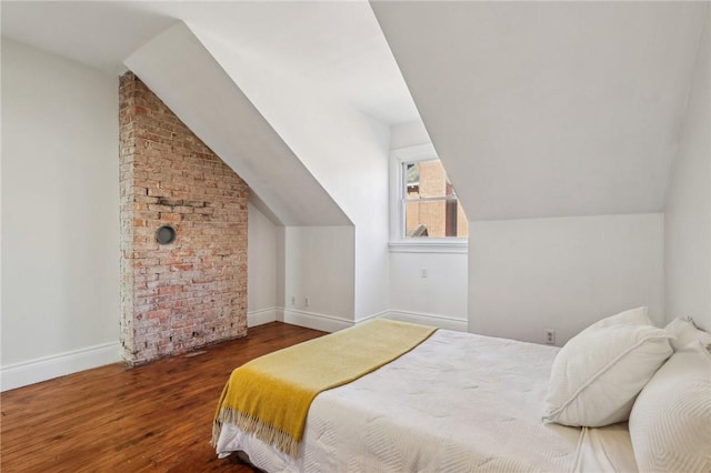 bedroom with vaulted ceiling, wood finished floors, and baseboards