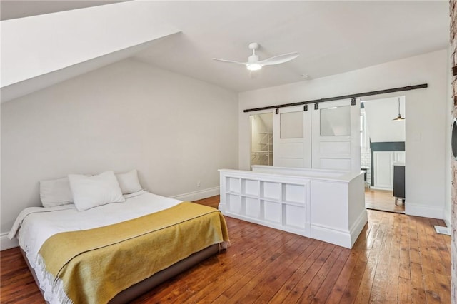 bedroom with a barn door, baseboards, a ceiling fan, vaulted ceiling, and light wood-type flooring