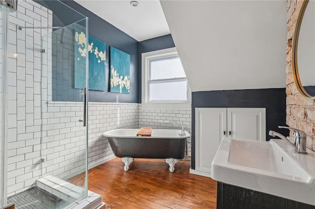 full bathroom featuring tile walls, a freestanding bath, a sink, a shower stall, and wood finished floors