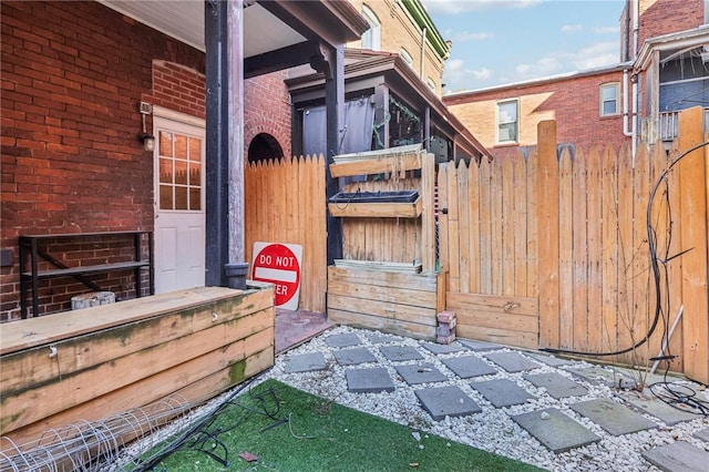 view of side of property featuring a gate, fence, and brick siding