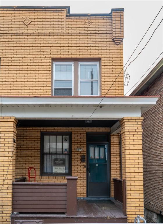 view of exterior entry with brick siding and a porch