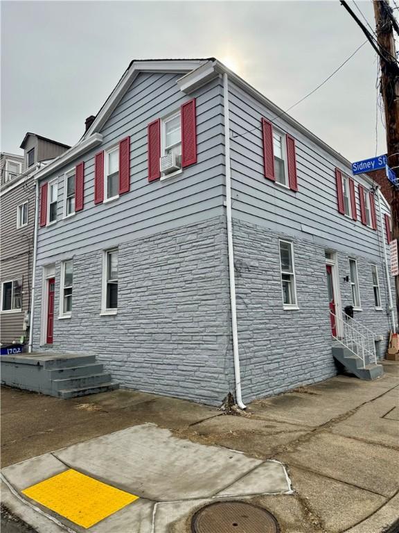 view of side of home featuring stone siding and cooling unit