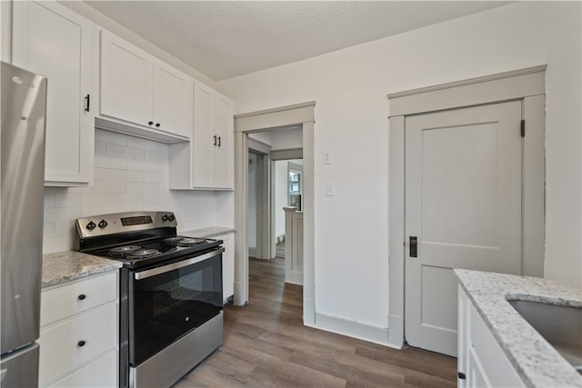 kitchen with stainless steel appliances, backsplash, white cabinetry, a textured ceiling, and wood finished floors