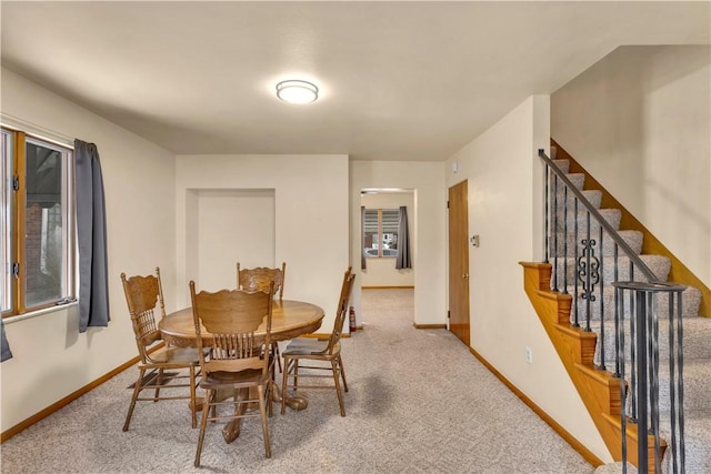 carpeted dining room featuring stairway and baseboards