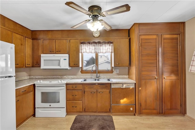 kitchen featuring light countertops, white appliances, brown cabinets, and a sink