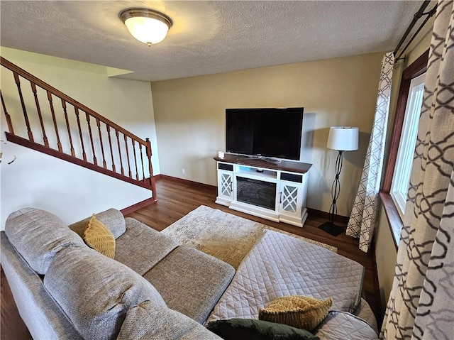 living area featuring a textured ceiling, stairs, baseboards, and wood finished floors