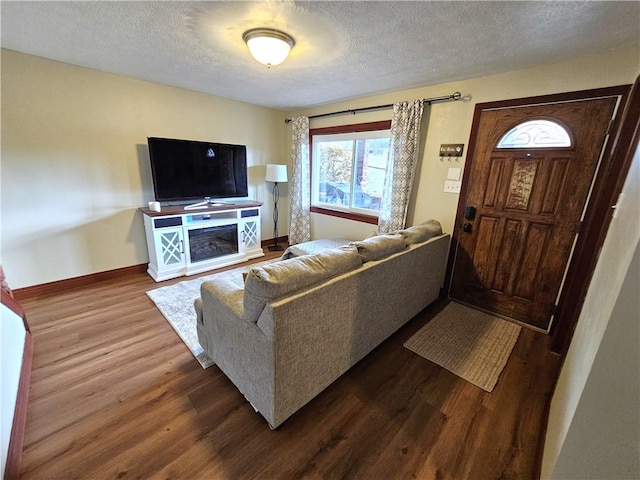 living area with a textured ceiling, baseboards, and dark wood-style flooring