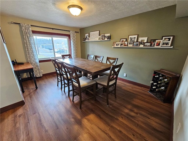 dining space featuring a textured ceiling, wood finished floors, and baseboards