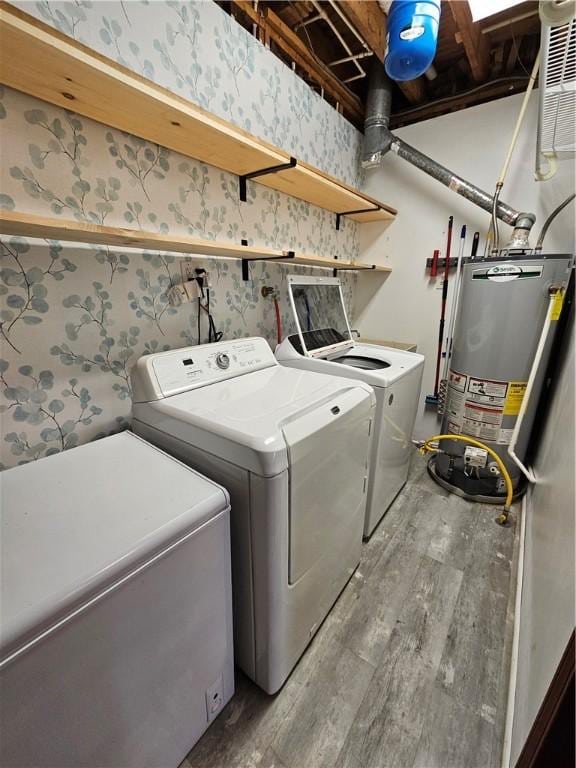 laundry area featuring laundry area, light wood-style floors, water heater, washer and dryer, and wallpapered walls