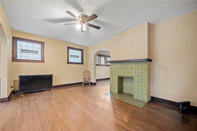 living room with baseboards, a tiled fireplace, and hardwood / wood-style floors