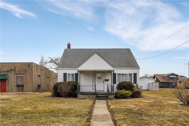 view of front facade featuring a shingled roof, a front yard, and a chimney