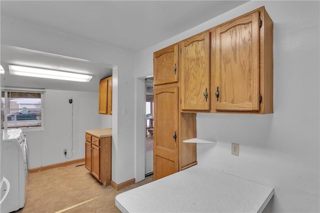 kitchen with brown cabinets, washing machine and dryer, baseboards, and light countertops