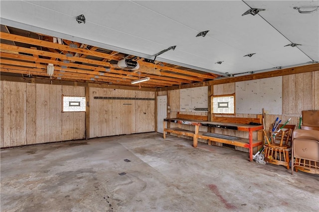 garage featuring a garage door opener, wooden walls, and a workshop area