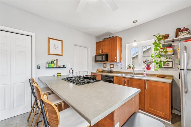 kitchen with brown cabinetry, light countertops, a sink, and black appliances