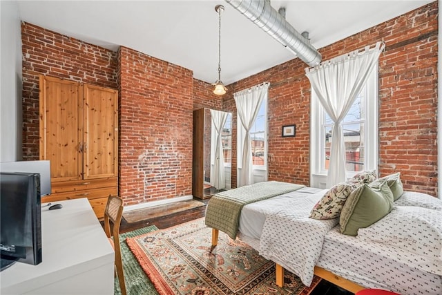 bedroom featuring brick wall and wood finished floors