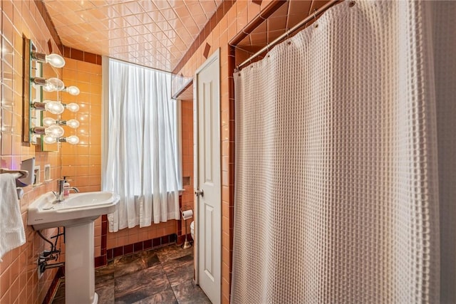 full bath featuring stone finish floor, tile walls, and a shower with shower curtain