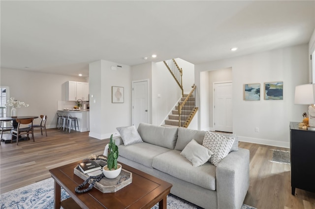 living room with light wood-style flooring, recessed lighting, and stairway