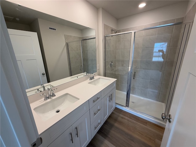 bathroom with a stall shower, visible vents, a sink, and wood finished floors