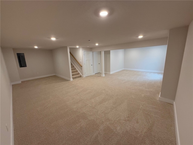 finished below grade area featuring light carpet, electric panel, baseboards, stairs, and recessed lighting