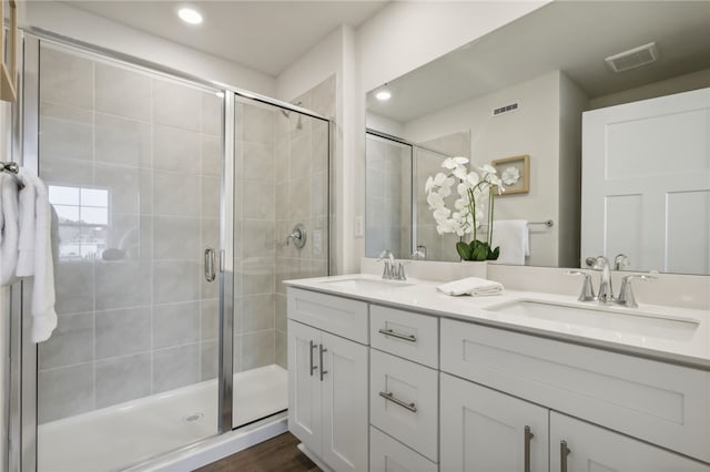 bathroom featuring visible vents, a sink, and a shower stall