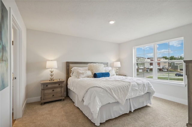 bedroom with baseboards and light colored carpet