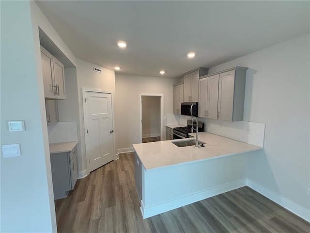 kitchen featuring stainless steel appliances, a peninsula, gray cabinetry, and wood finished floors