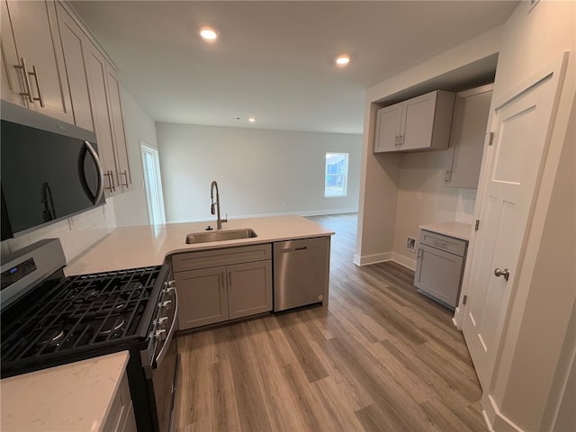 kitchen featuring a peninsula, appliances with stainless steel finishes, gray cabinets, and a sink