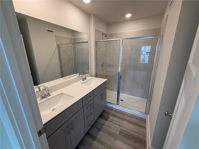 bathroom with wood finished floors, a sink, and a shower stall