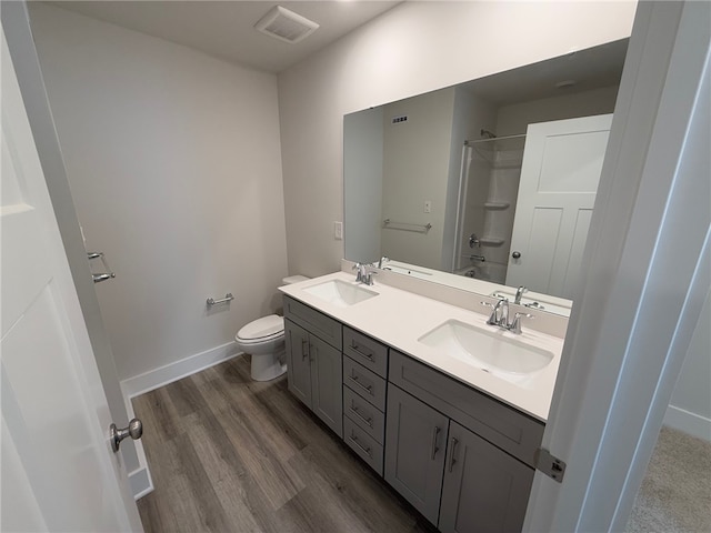 full bathroom with toilet, double vanity, baseboards, and a sink