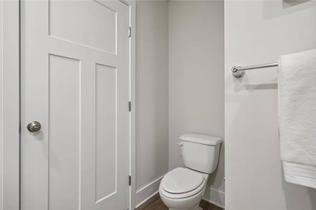 bathroom with wood finished floors, toilet, and baseboards