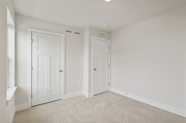 unfurnished bedroom with carpet floors, visible vents, and baseboards