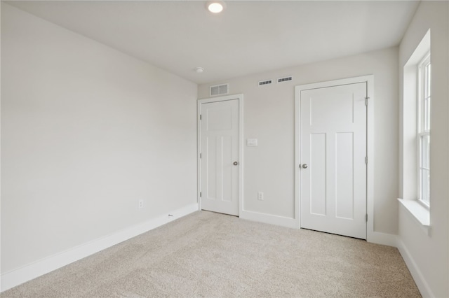 unfurnished bedroom with carpet, visible vents, and baseboards